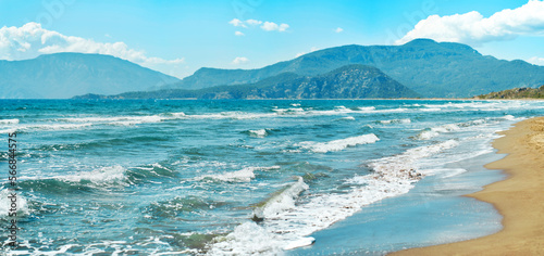 Fototapeta Naklejka Na Ścianę i Meble -  Seascape with waves at sunny day at beautiful sandy empty beach. Beautiful mountain range on background. Iztuzu in Turkey