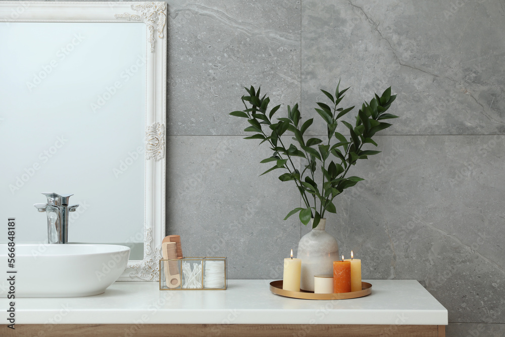 Fototapeta premium Beautiful plant in vase and burning candles near vessel sink on bathroom vanity