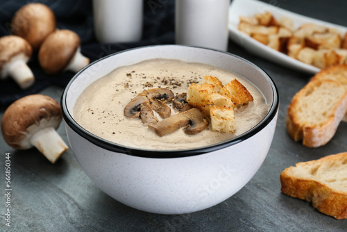 Delicious cream soup with mushrooms and croutons on black table, closeup