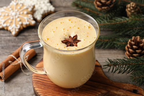 Glass of delicious eggnog with anise star on wooden table
