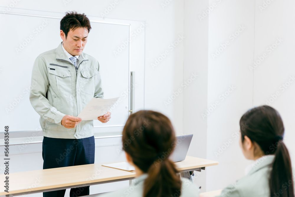 Obraz premium 工場・会社・オフィス・会議室で会議・セミナー・勉強会の講師をするエンジニア・技術者・作業員の男性