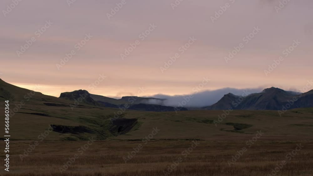 Beautiful sunset over grassy plains and mountains in southern Iceland. Clouds rolling in over the mountains. Beautiful sunset over grassy plains and mountains in southern Iceland. Clouds rolling in over the mountains.