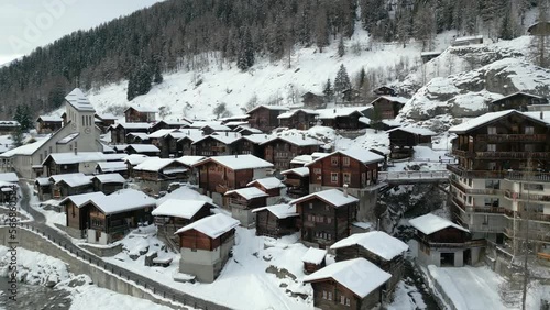 An old Swiss mountain village in winter. Blatten in the Lötschental valley in Switzerland. The church is in the middle of the village. Everything is covered with snow. photo