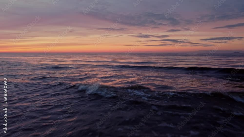 Low aerial drone flying above sea water waves at striking orange sunset sky Low aerial drone flying above sea water waves at striking orange sunset sky