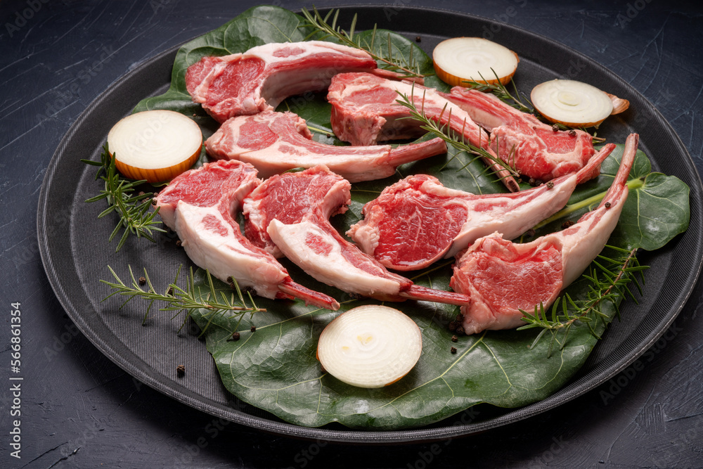 Lamb chops with rosemary and onion in black plate on wooden background, Fresh Raw lamb loin on black Background. Lamb chops with rosemary and onion in black plate on wooden background, Fresh Raw lamb loin on black Background.