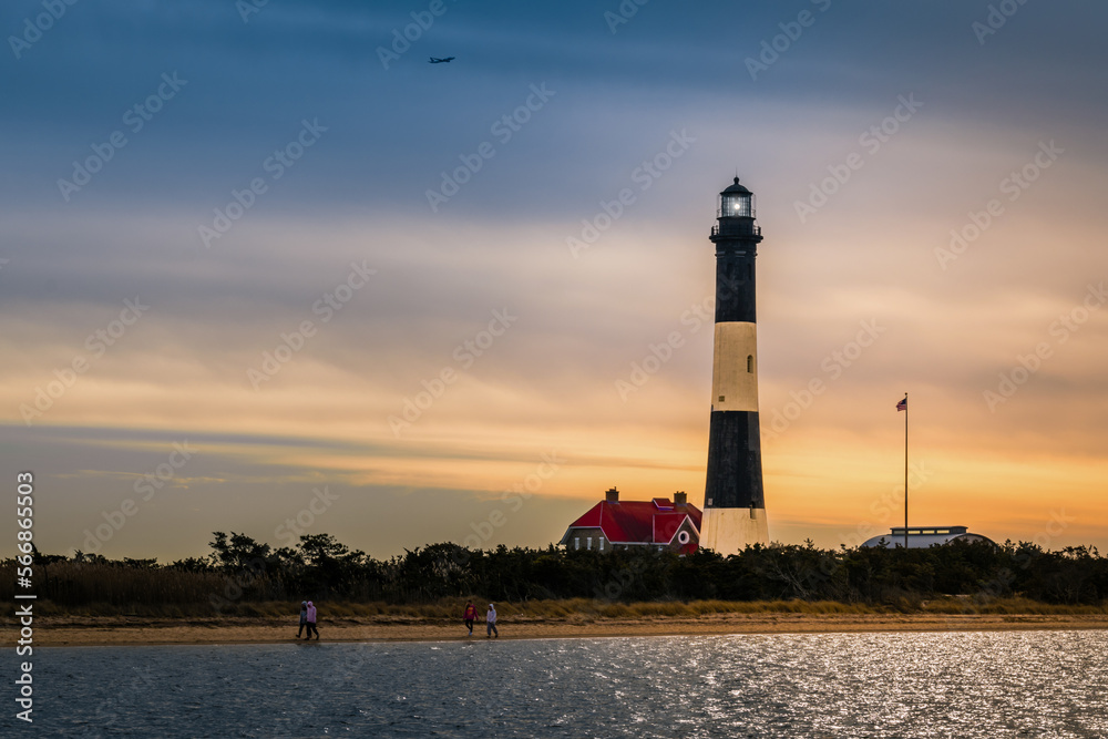 The Fire Island Lighthouse  on the Great South Bay,  Long Island, New York,  with tourists on the beach and ocean water in the foreground