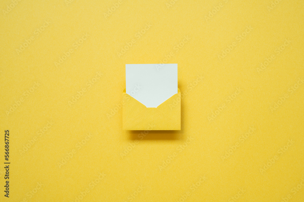 Yellow envelope with white blank card on yellow background. top view, copy space, minimalism Yellow envelope with white blank card on yellow background. top view, copy space, minimalism