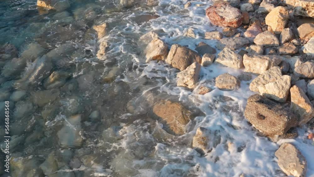 Waves crashing on the rocky shore and lapping on the beach covered with stones - sea or ocean coast. Power of water as natural resource and global warming. Waves crashing on the rocky shore and lapping on the beach covered with stones - sea or ocean coast. Power of water as natural resource and global warming.
