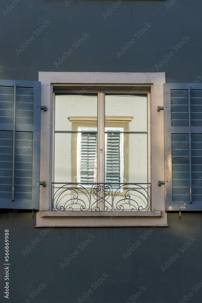 Fototapeta premium A window perfectly reflected inside of another window, amidst a dark blue wall
