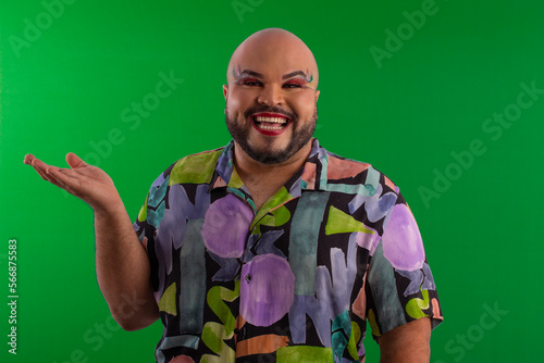 fat lgbt man, with makeup and printed shirt in studio shot with green background making facial expressions