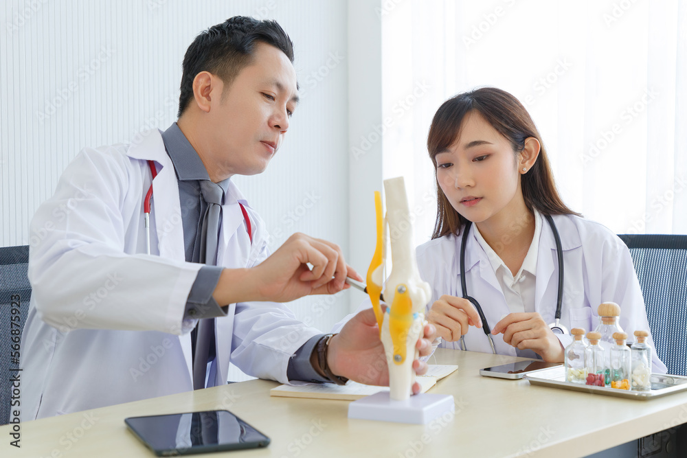 Orthopedic professional doctor and intern doctor interact and sitting togetherr, talking about knee pain treatment in medical office. Orthopedic professional doctor and intern doctor interact and sitting togetherr, talking about knee pain treatment in medical office.