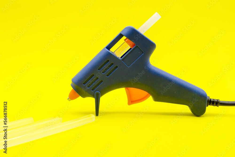 Blue glue gun close-up on a yellow background Blue glue gun close-up on a yellow background