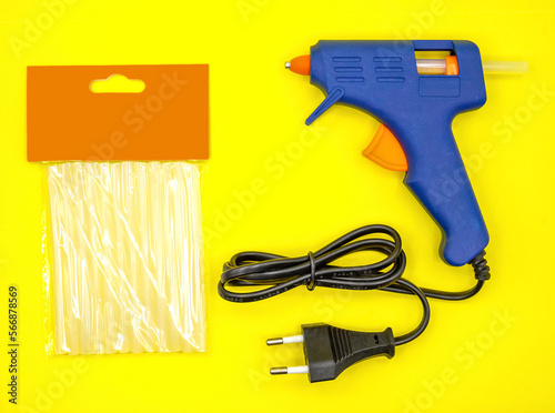 Blue glue gun close-up on a yellow background