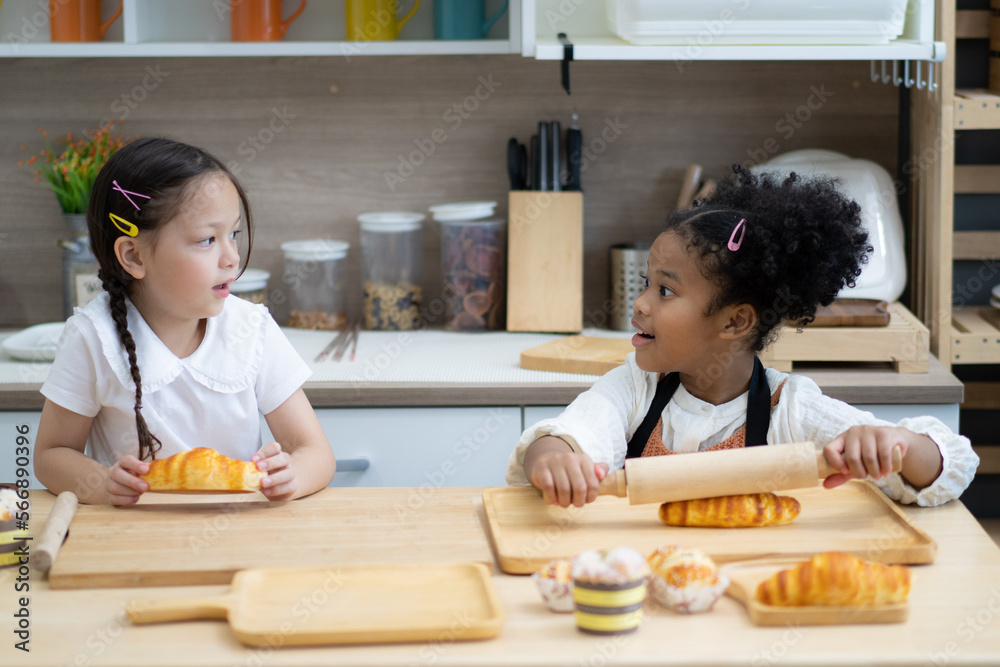 Two happy little kids siblings cooking together, rolling out dough, standing at wooden countertop in modern kitchen homemade. Two happy little kids siblings cooking together, rolling out dough, standing at wooden countertop in modern kitchen homemade.