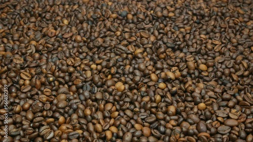 A cup of hot coffee stands on the table next to coffee beans. Cinnamon sticks for coffee are very tasty. Coffee beans background for advertising. photo