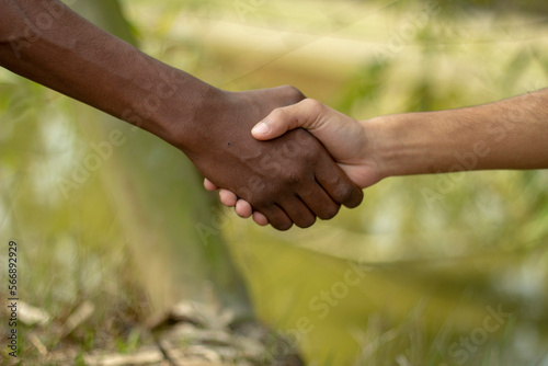 there is two hands a black and a white hand meet one another hand and the background is blurred © Rokonuzzamnan