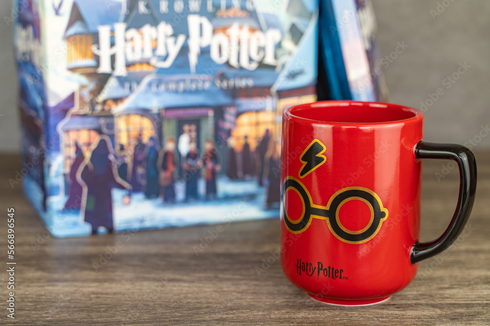 Fototapeta premium Harry Potter mug and stack of books on background. Harry Potter themed items for fans.