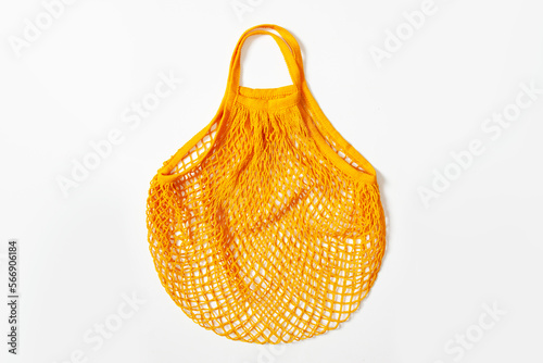 mesh grocery bag. Reusable bag. Vegetarianism, raw food diet, conscious consumption, grid. mesh bag in orange on a white background. View from above
