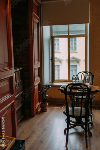 Wooden table with two wooden chairs in the hotel room on the background of the window