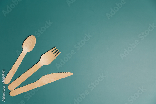 Wooden biodegradable single use utensils on a green background