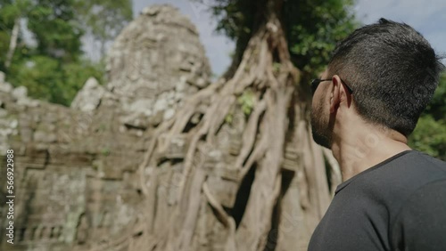 Male Tourist Gazing at The Khmer temple of Ta Som - Tree growing atop the historical main gateway photo