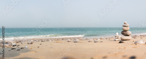 Zen image with pile of pebbles on a sand beach in front of the sea. Sunrise zen, calm and peaceful concept with cairn