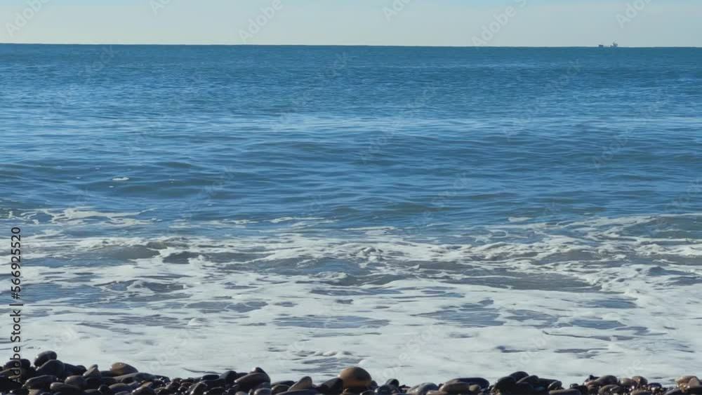 Powerful sea waves are crashing on the Black Sea coast. Sea waves splash on the beach with pebbles in the rays of the sun. Russia, Agoi Powerful sea waves are crashing on the Black Sea coast. Sea waves splash on the beach with pebbles in the rays of the sun. Russia, Agoi