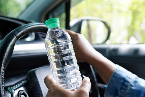 Asian woman driver hold cold water for drink in car, dangerous and risk an accident.