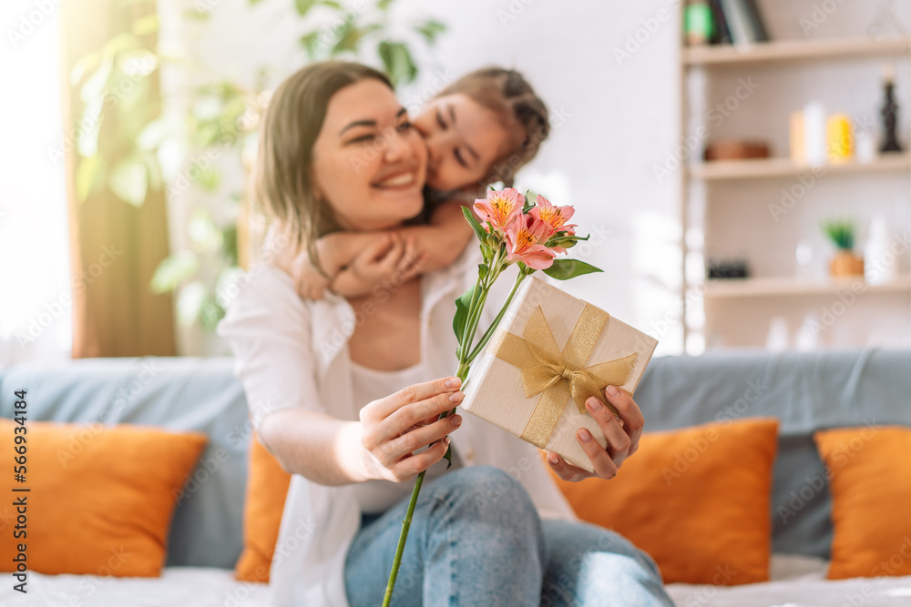 Daughter hugged her mother and gave a gift and flowers. mother's day - obrazy, fototapety, plakaty 