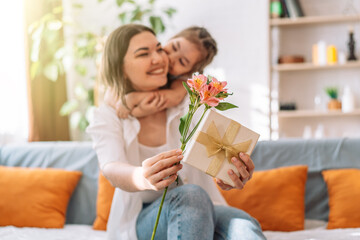 Daughter hugged her mother and gave a gift and flowers. mother's day