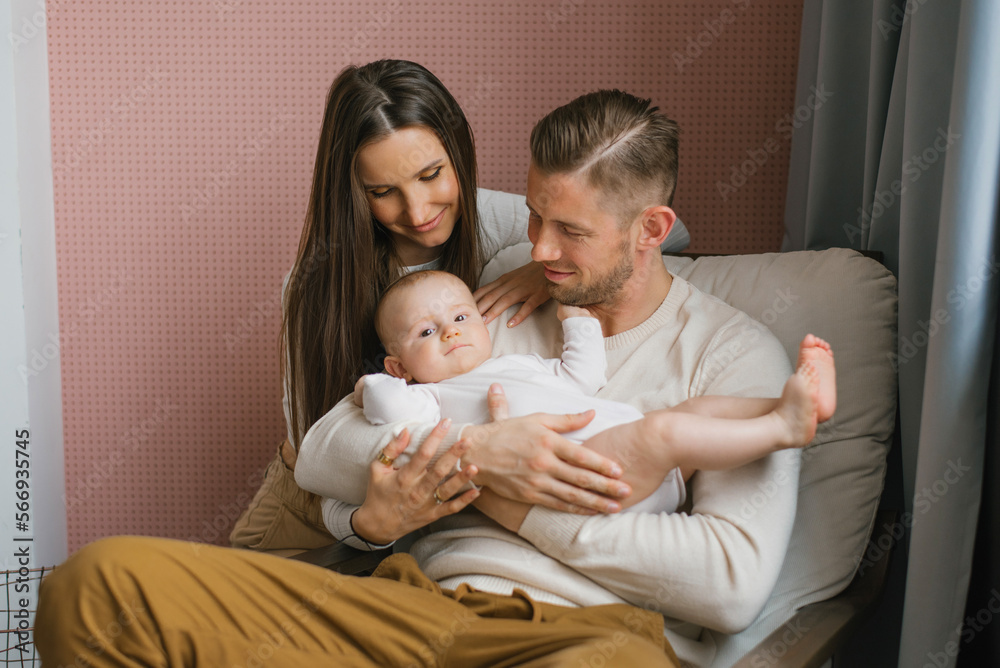 Young happy parents hold their baby son in their arms and smile looking at him Young happy parents hold their baby son in their arms and smile looking at him