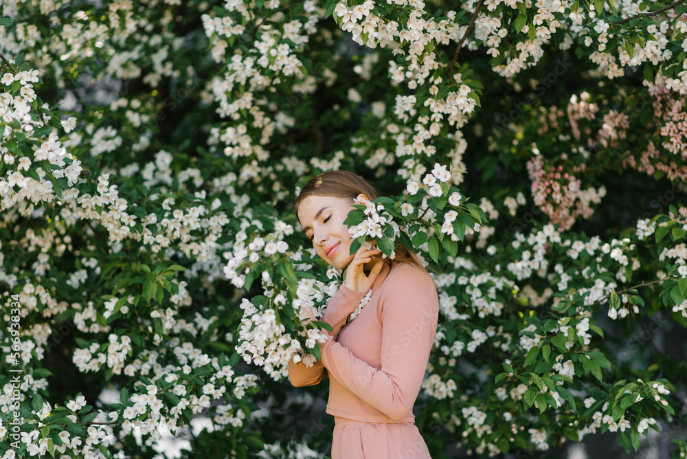 A beautiful young woman enjoys life in a spring blooming garden against the background of blooming apple trees. A beautiful young woman enjoys life in a spring blooming garden against the background of blooming apple trees.