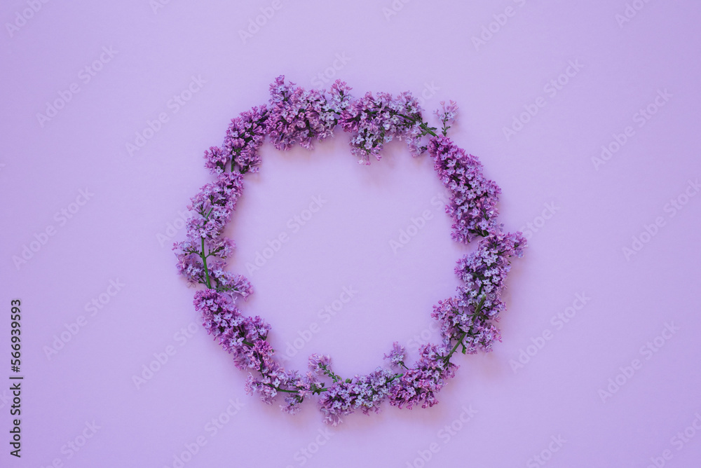 Round frame of lilac flowers on a lilac background. Copy space, flat lay