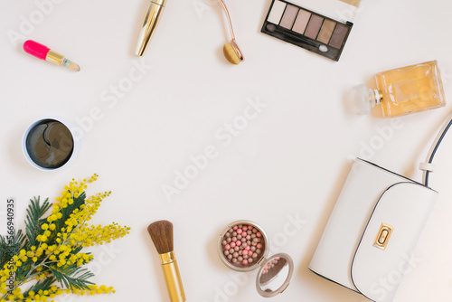 A composition with women's accessories, cosmetics and yellow flowers on a colored background. The concept of a beauty blogger
