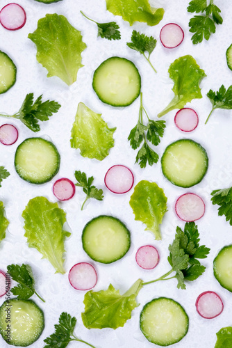  vegetable background of lettuce leaves, cucumber slices, radishes and parsley leaves on a white background. The concept of proper nutrition