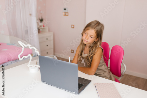 Cute schoolgirl student with laptop online lesson video call conference call, remote quarantine, study and homework