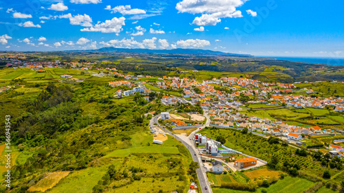 Aerial view to scenic urban landscape on summer sunny day. Beautiful cityscape with skyline. Tourist region of Portugal on summer. Small european village on a green valley with ocean on background.