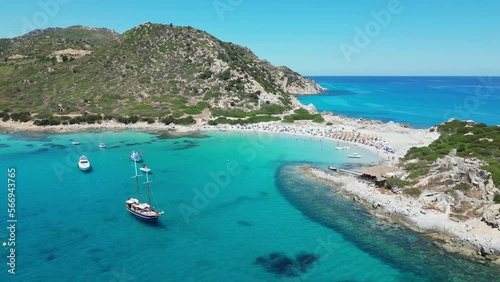 Punta Molentis Beach in Villasimius, Sardinia - Boats and Tourists in Turquoise Blue Sea and Small White Sandy Beach - Aerial 4k Circling photo