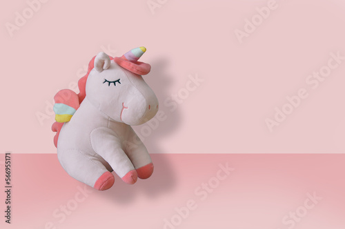Cute soft unicorn plush toy on pink background. Close up shot, empty space