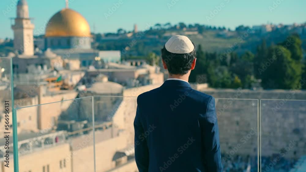 A bar mitzvah boy stands with his back to the camera on a balcony with a view of the Western Wall in the morning. Taking a beautiful video from a Bar Mitzvah ceremony. A bar mitzvah boy stands with his back to the camera on a balcony with a view of the Western Wall in the morning. Taking a beautiful video from a Bar Mitzvah ceremony.