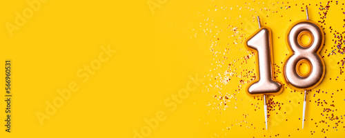 Gold candles in the form of number eighteen on yellow background with confetti. 18 years celebration. Greeting banner. photo