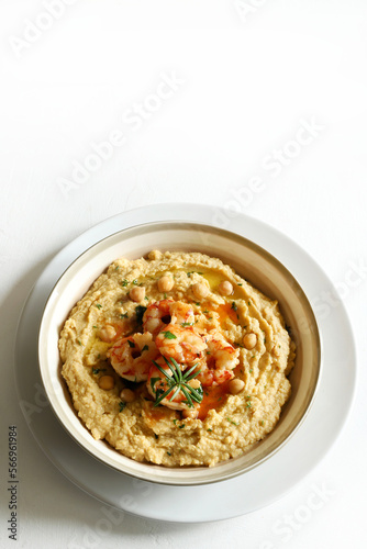 Ciotola con hummus, gamberi, erbe aromatiche e pane tostato su sfondo bianco. Direttamente sopra.