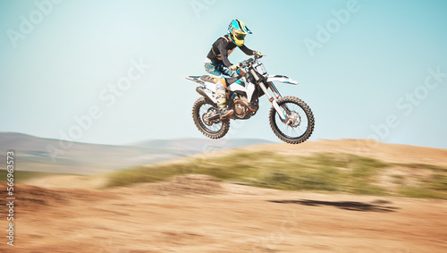 Motorcycle, offroad driving and air jump in desert, blue sky and freedom. Driver, cycling and power stunt on dirt track, competition and motorbike performance on adventure course for fast action show © J Bettencourt/peopleimages.com