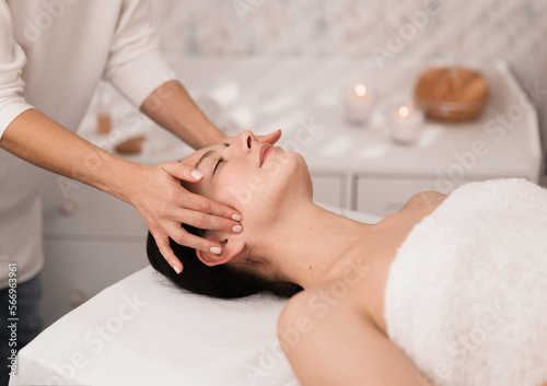 Crop unrecognizable therapist massaging face of female patient