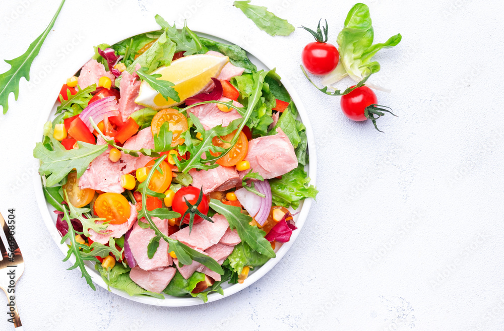 Tuna vegetables salad with colorful cherry tomatoes, red onion, sweet corn, paprika, lettuce, radicchio and arugula. White table background, top view Tuna vegetables salad with colorful cherry tomatoes, red onion, sweet corn, paprika, lettuce, radicchio and arugula. White table background, top view