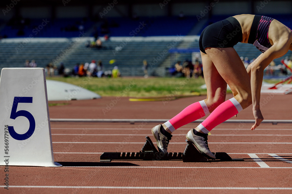 girl athlete in compression socks running from starting blocks