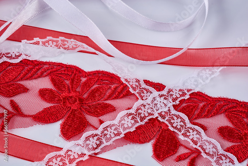 Various red and white lace and satin ribbons lie on a white table, close-up.