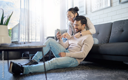 Interracial, couple and people with phone on social media laughing at meme or funny internet content. Man, woman and lovers relax in home, house or apartment browsing the web, website or app