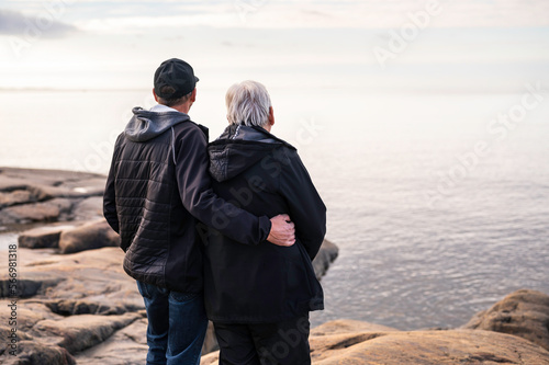 Elderly couple standing on a rocky beach. Looking towards the horizon. Fäboda, Jakobstad/Pietarsaari, Finland.