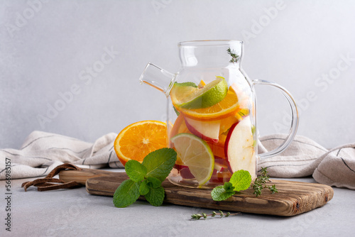 Glass teapot for healthy fruit tea with fresh ripe citrus, apples, mint and thyme